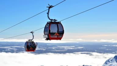 Dos funiculares rojos con el logotipo "YLLAS" sobrevolando un paisaje nevado.
