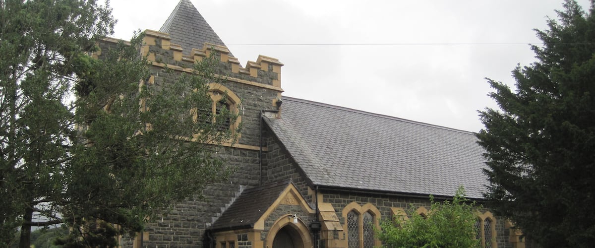 A stone church with a pointed steeple and arched windows.