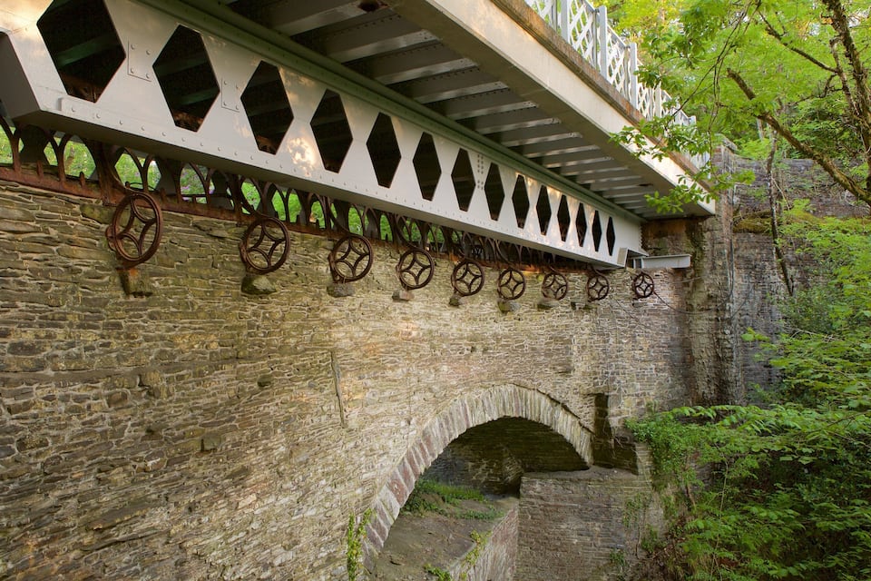 Un pont en pierre orné de roues métalliques décoratives et doté d’une balustrade blanche.