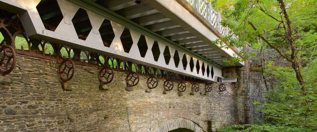 A stone bridge with decorative metal wheels and a white railing.