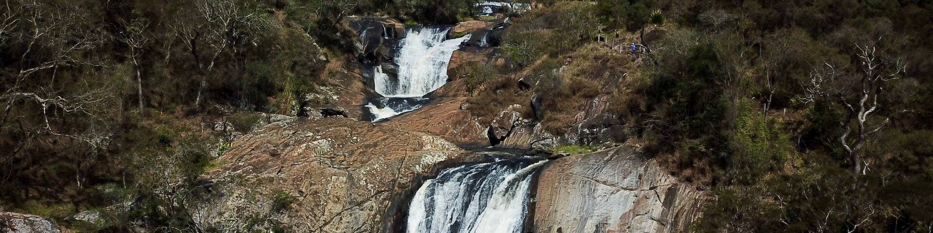A waterfall cascading over rocky terrain surrounded by dense forest.