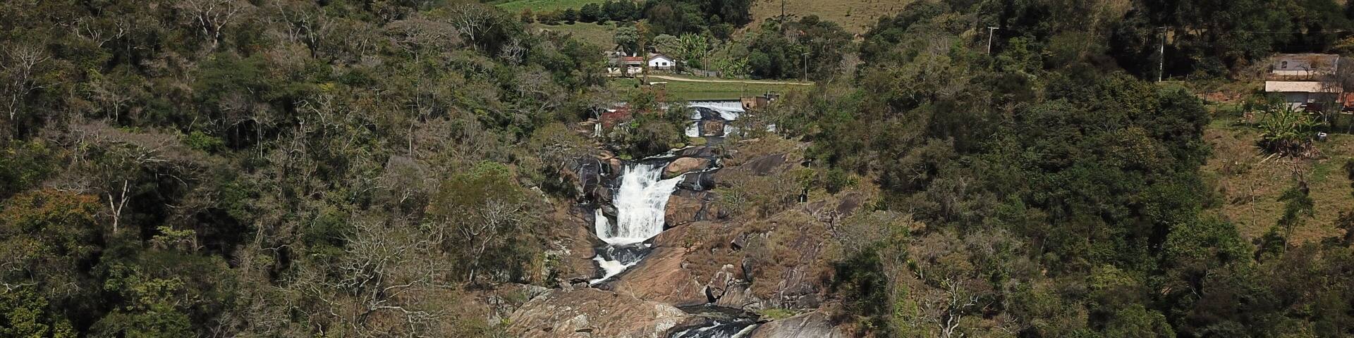 A waterfall cascading down a rocky cliff surrounded by dense forest.