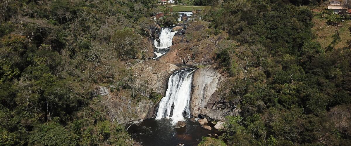 A waterfall cascading down a rocky cliff surrounded by dense forest.