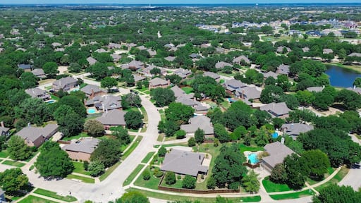 Master planned community with neighborhood pond water fountain, mature trees surrounding row of upscale two-story houses, swimming pool, in Keller, Tarrant County, Texas, suburbs Dallas, aerial