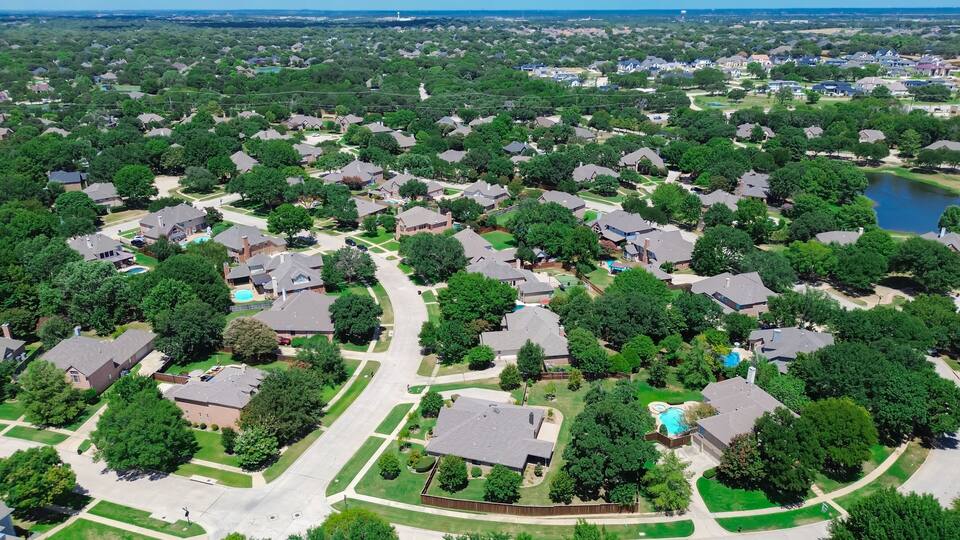 A suburban neighborhood with houses, green lawns, and a lake.