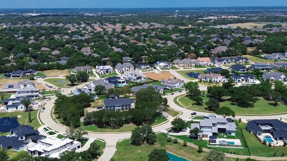 A suburban neighborhood with houses, roads, and a large body of water.