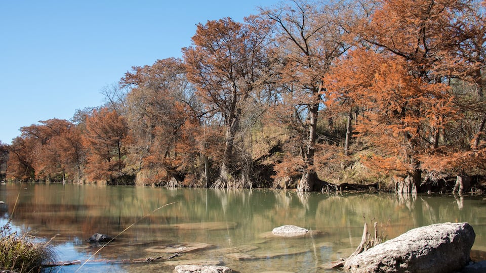 A calm lake surrounded by autumn-colored trees.