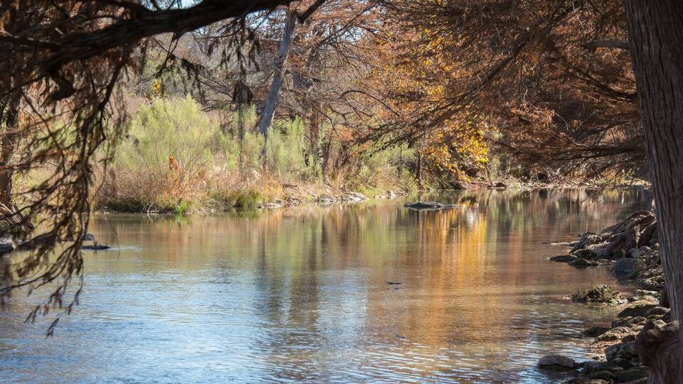 A calm river with reflections of trees and rocks.