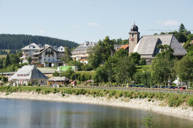 A lakeside town with historic buildings, a church, and a bridge.