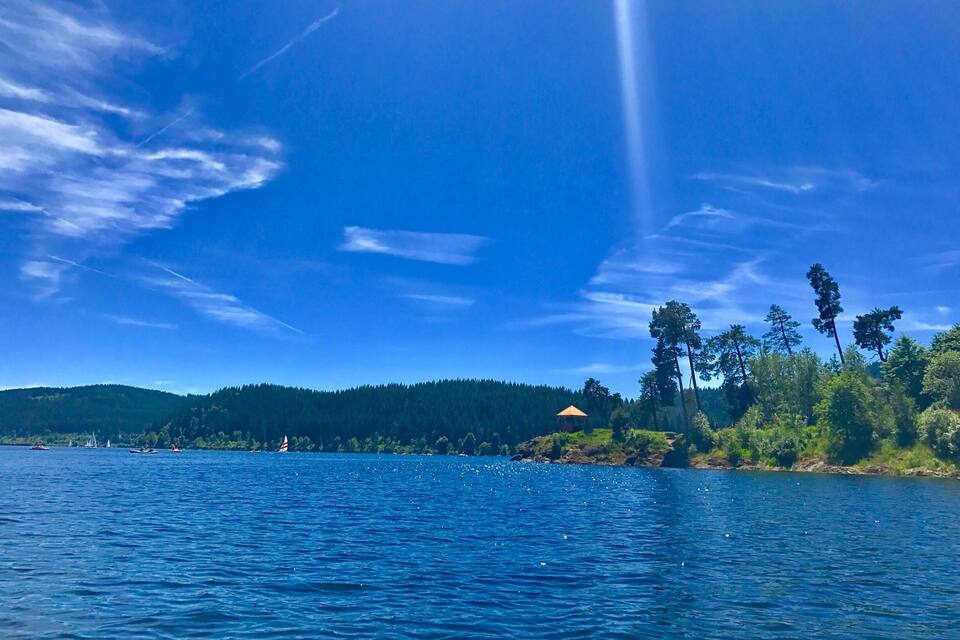 Un llac amb barques, una riba boscosa i un cel serè.