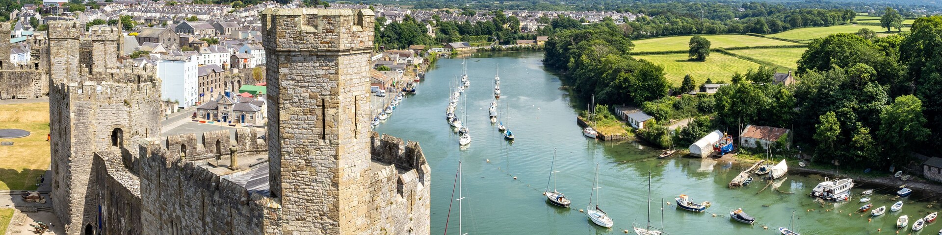 Um castelo histórico com vista para um rio e barcos.