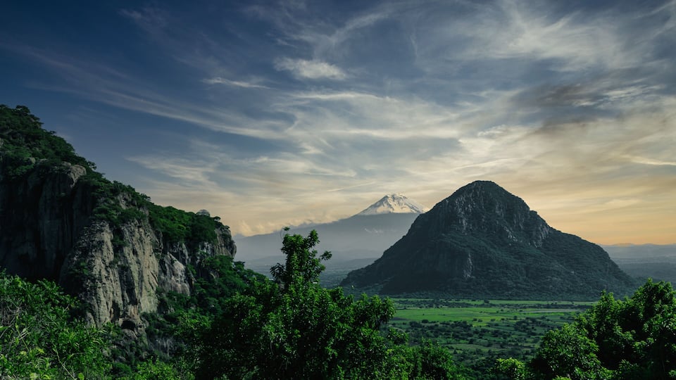 A mountainous landscape with a prominent peak, lush greenery, and a valley.