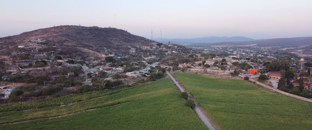 A rural landscape with fields, a hill, and scattered houses.