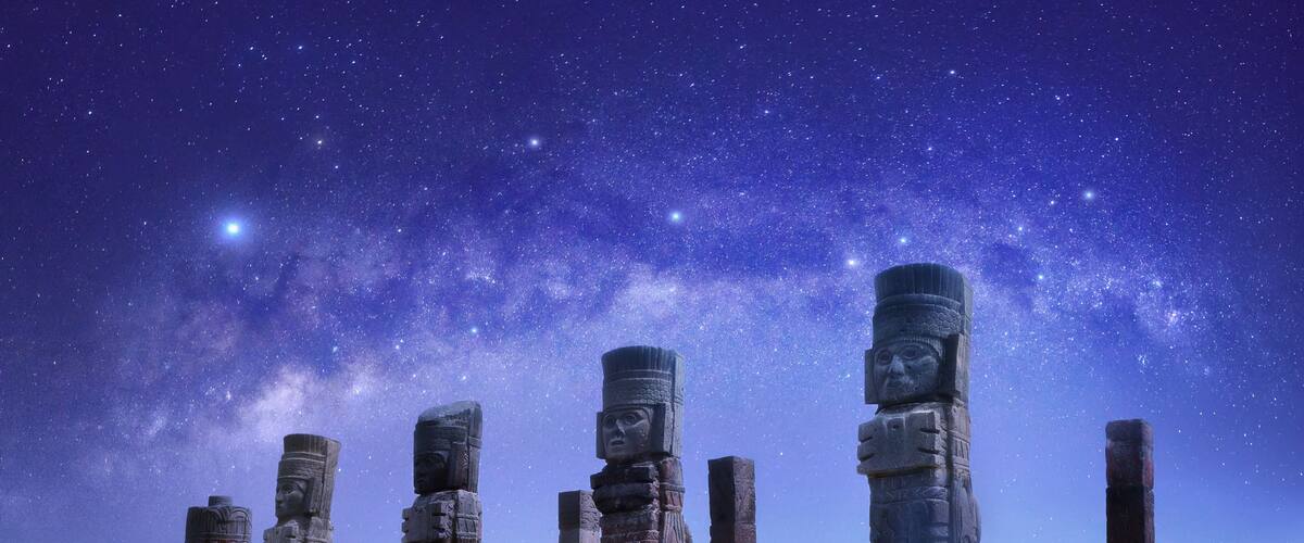 Ancient stone statues under a starry night sky.