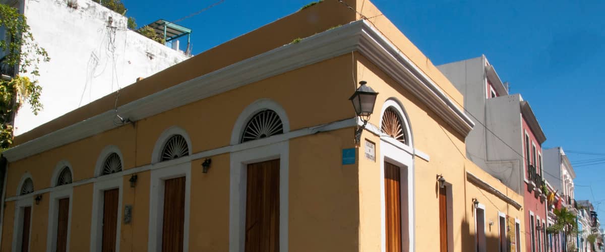 A yellow building with arched windows and a blue handicap-accessible ramp on a cobblestone street.