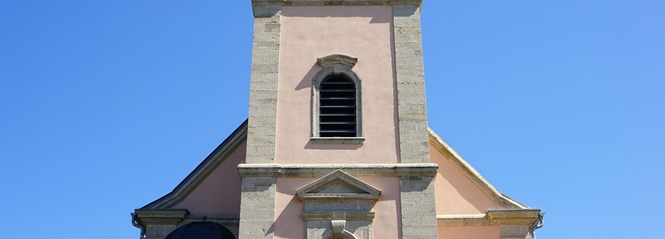 Igreja com uma torre alta de sino e uma estátua em frente.