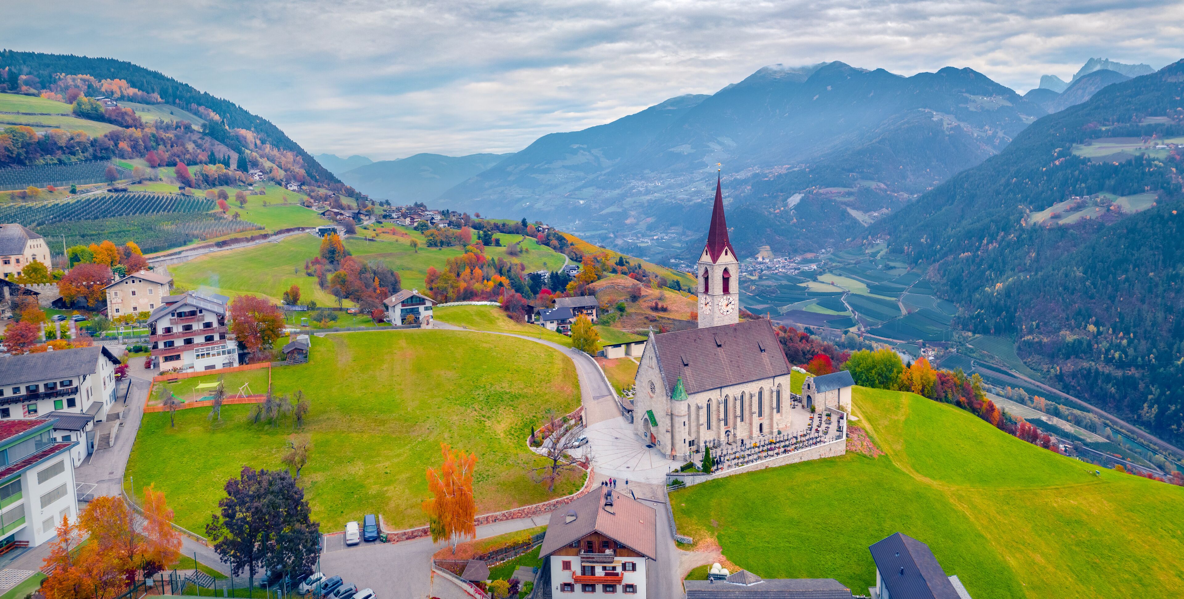 Gloomy autumn view from flying drone of Pfarrkirche Feldthurns Church. Aerial evening cityscape of Velturno village, Province of Bolzano, South Tyrol, Italy, Europe. Traveling concept background..