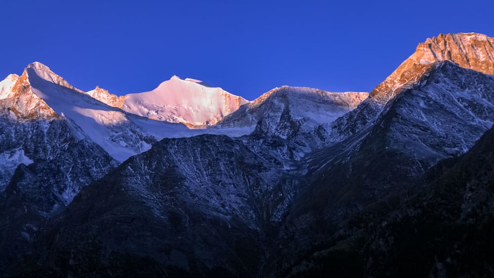 Une chaîne de montagnes dont les sommets enneigés se dressent sous un ciel bleu dégagé.