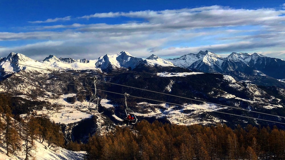 Ein verschneites Gebirge mit Skiliften und Skifahrern.