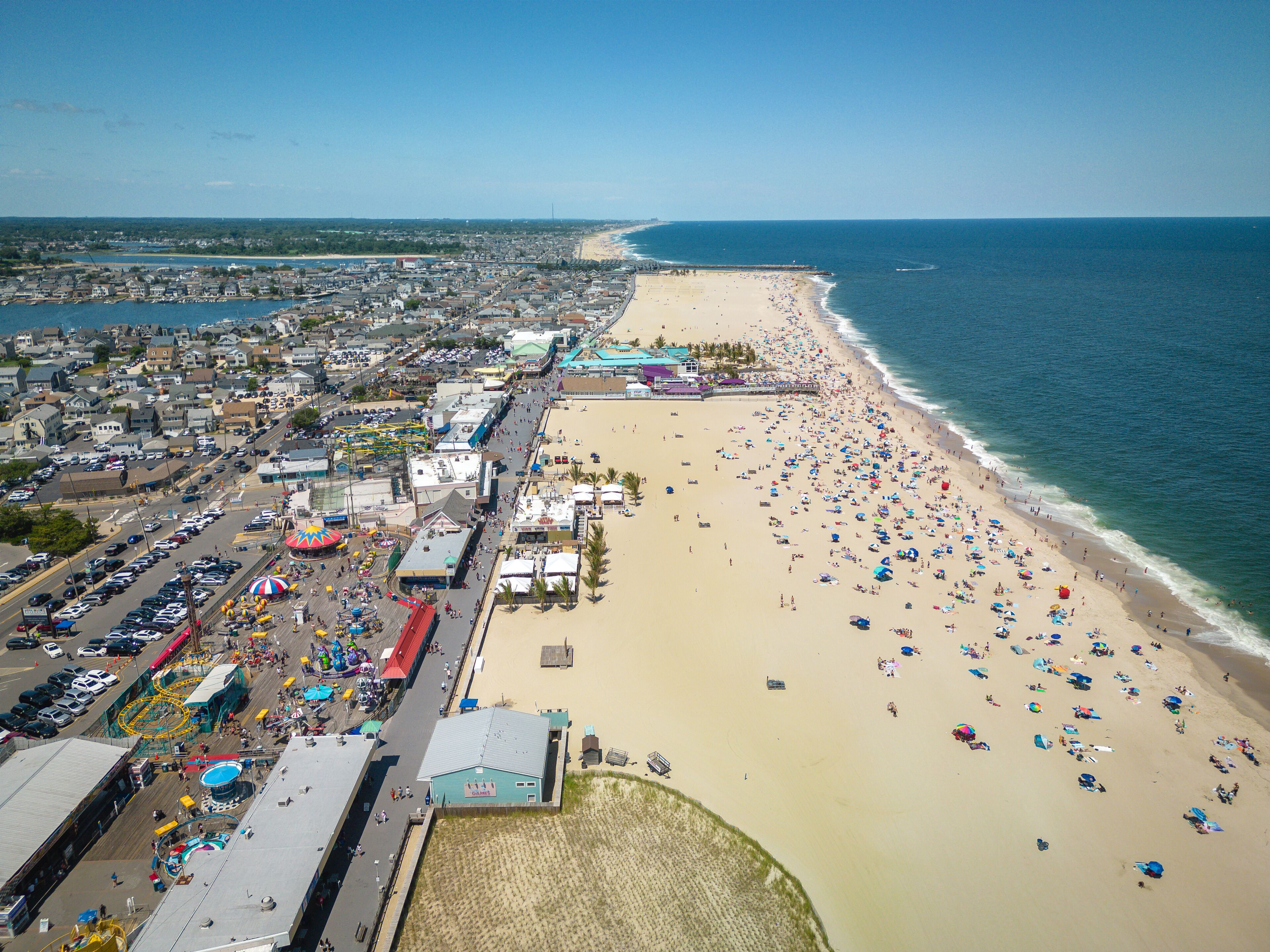 A coastal town with a crowded beach, a pier, and a carnival.