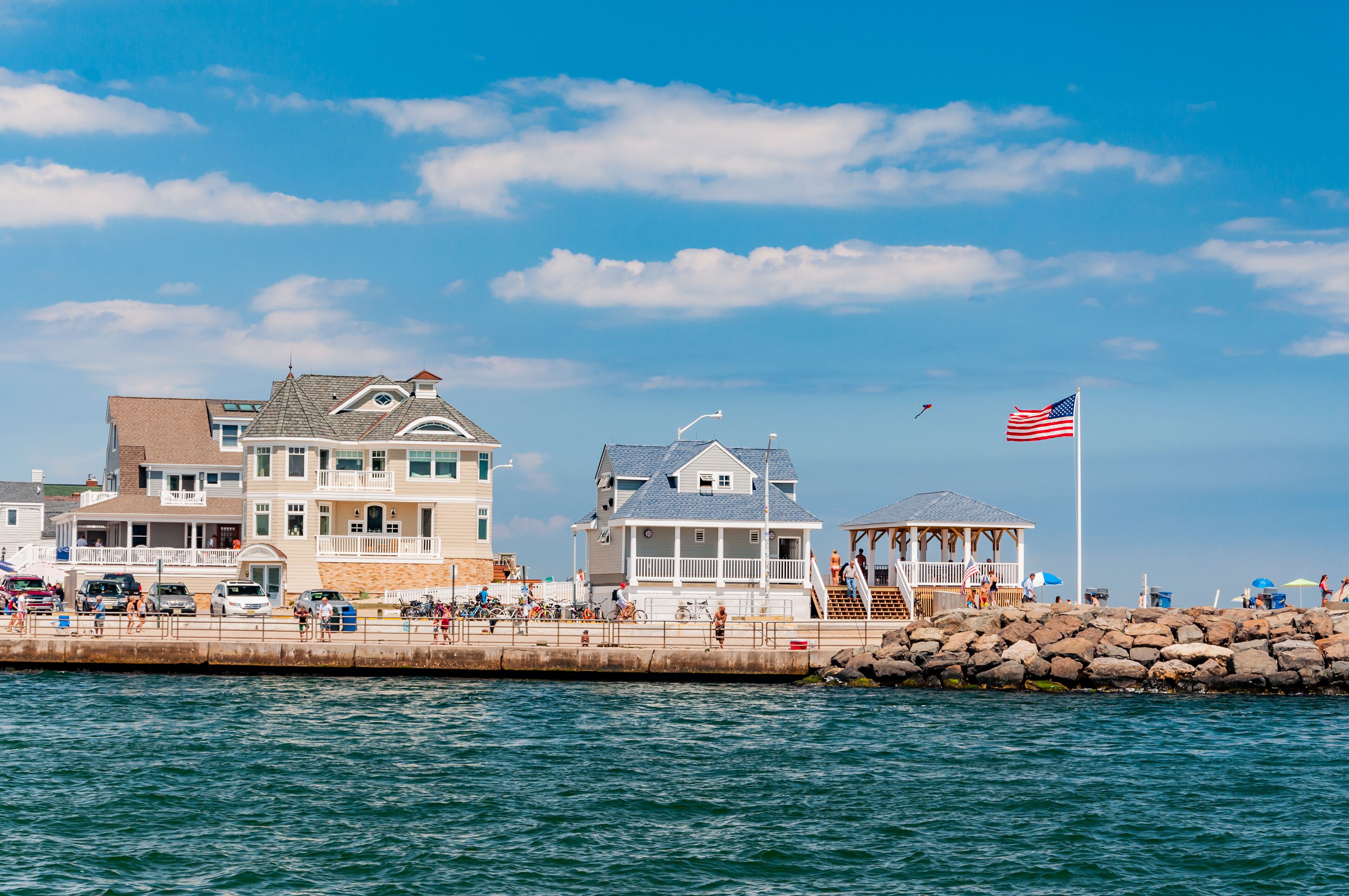 A coastal town with a pier, a gazebo, and a large house with a balcony overlooking the water.