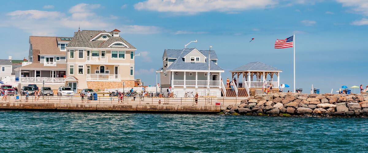 A coastal town with a pier, a gazebo, and a large house with a balcony overlooking the water.