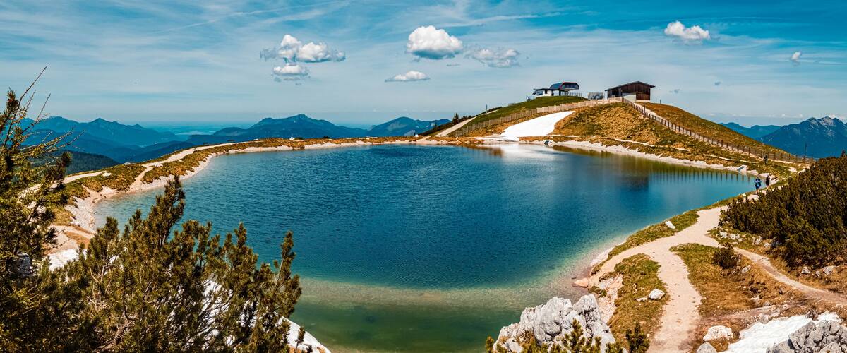 A lake surrounded by mountains, a wooden cabin, and a clear sky.