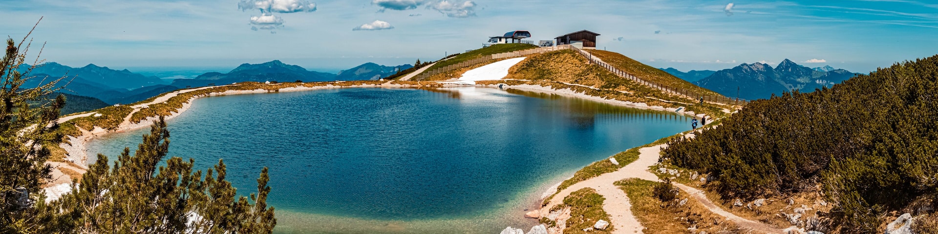 A lake surrounded by mountains, a wooden cabin, and a clear sky.