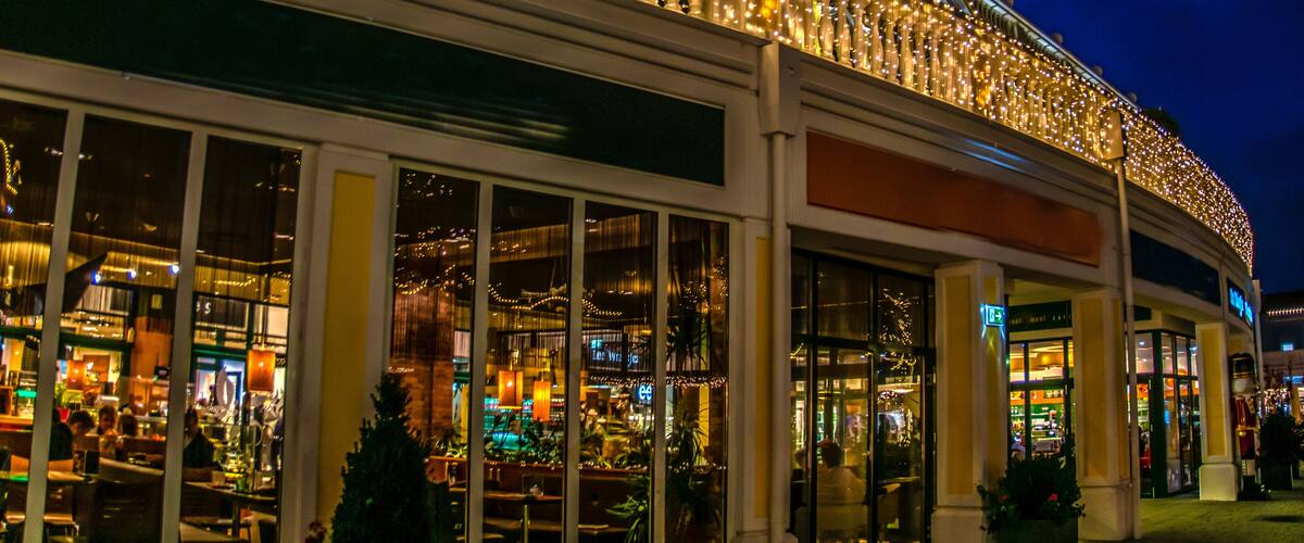 A brightly lit building with a balcony adorned with string lights and a Christmas tree.