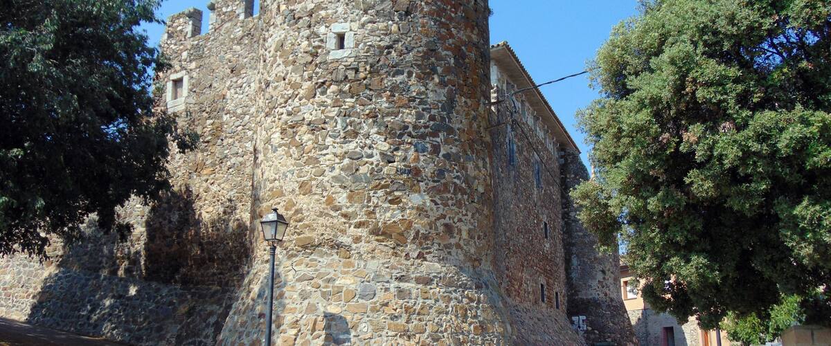 A stone tower with a rounded top, surrounded by trees and a street.