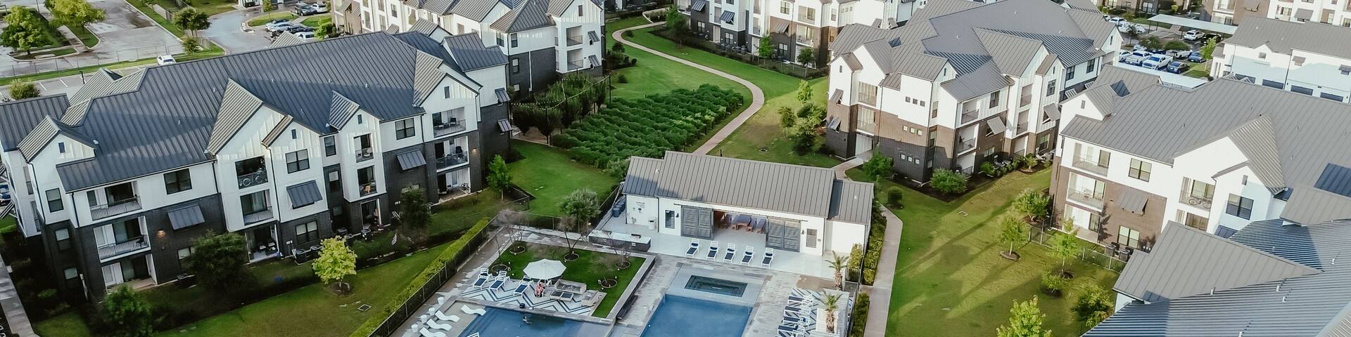 Panorama aerial view modern swimming pool spa in new development apartment complex, metal roofing, siding in fast growing area Pflugerville northeast of downtown Austin, Texas, housing market
