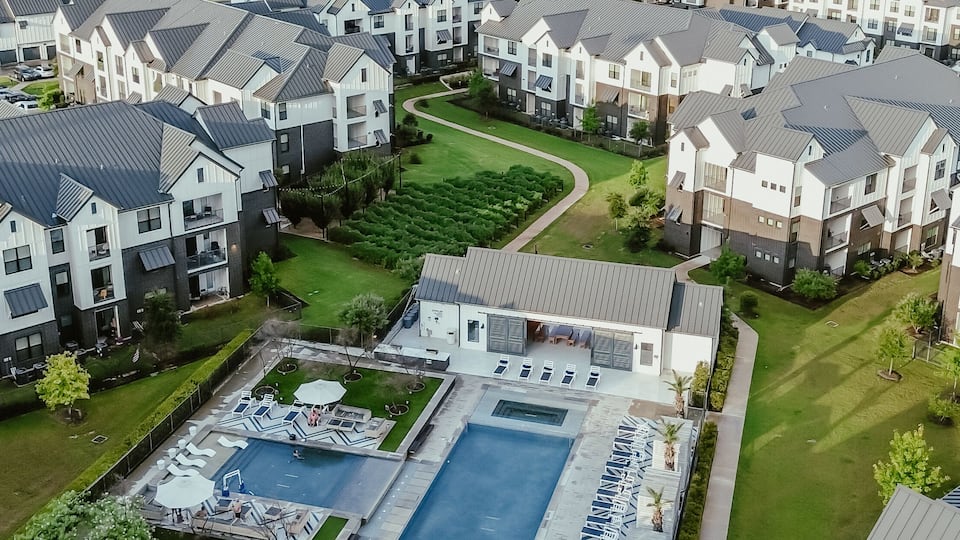 A residential area with modern houses, a swimming pool, and well-maintained lawns.