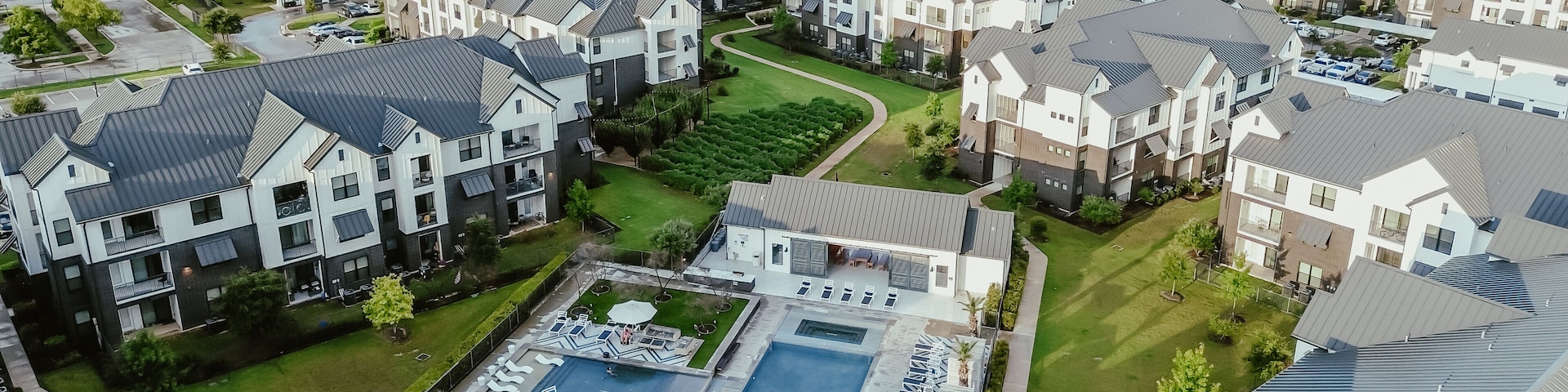 A residential area with modern houses, a swimming pool, and well-maintained lawns.