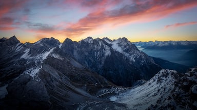 Een bergketen met besneeuwde toppen en een zonsonderganglucht.