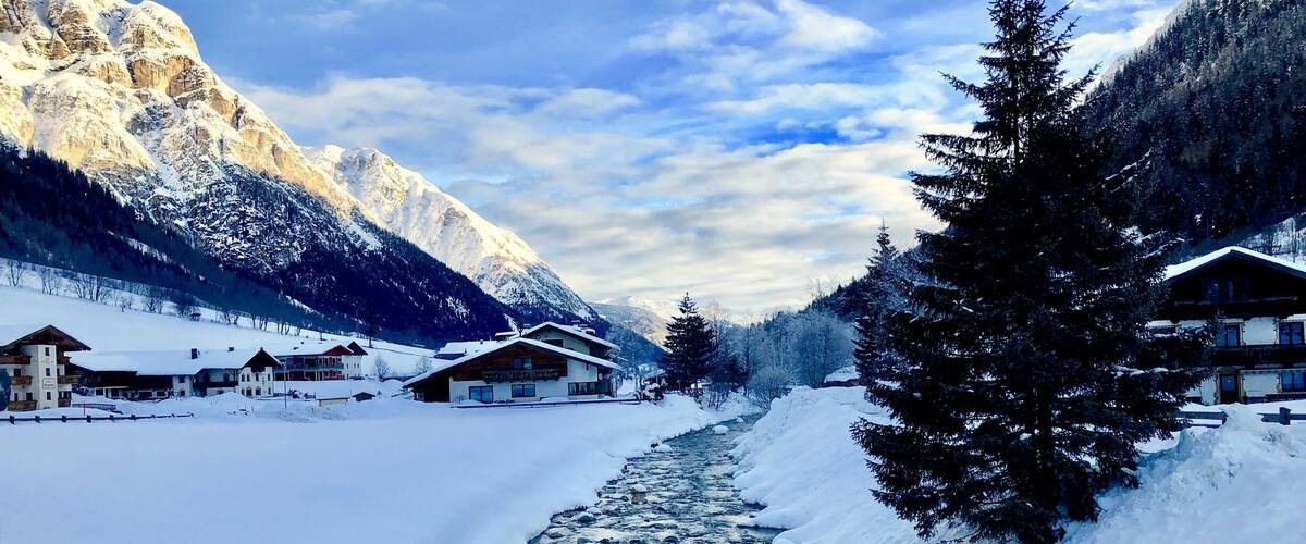 A snow-covered mountain landscape with a river flowing through a village.