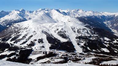 A snow-covered mountain range with ski slopes.