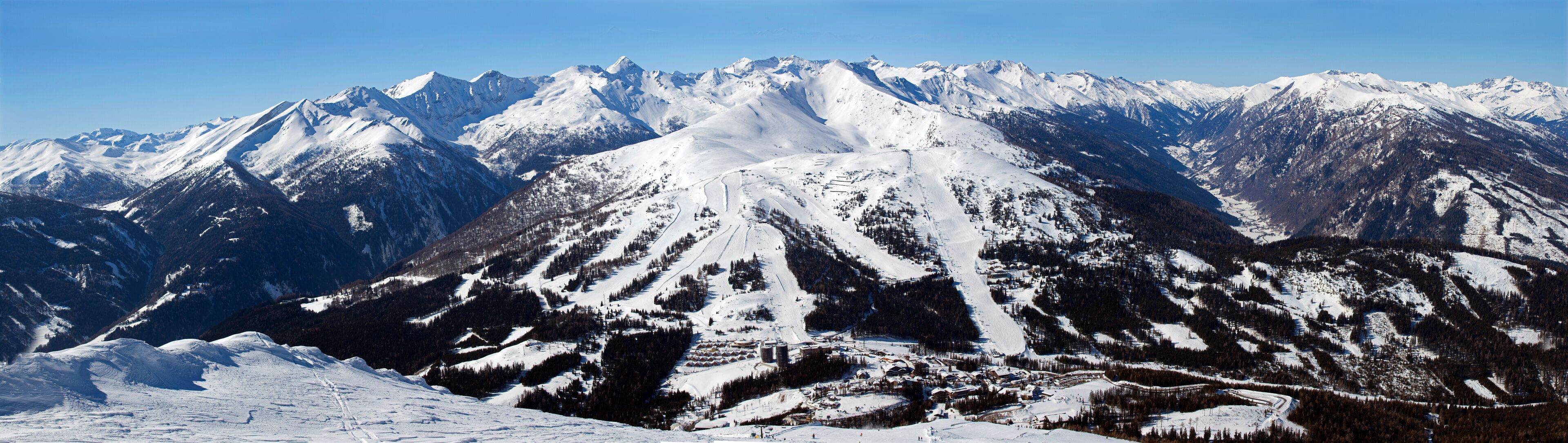 A snow-covered mountain range with ski slopes.