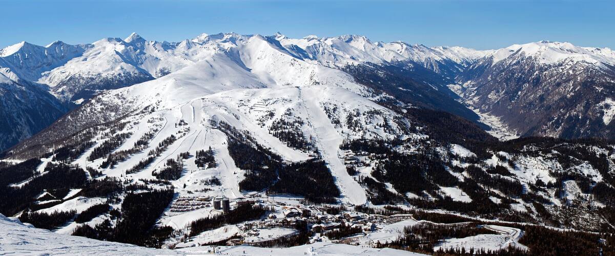 A snow-covered mountain range with ski slopes.