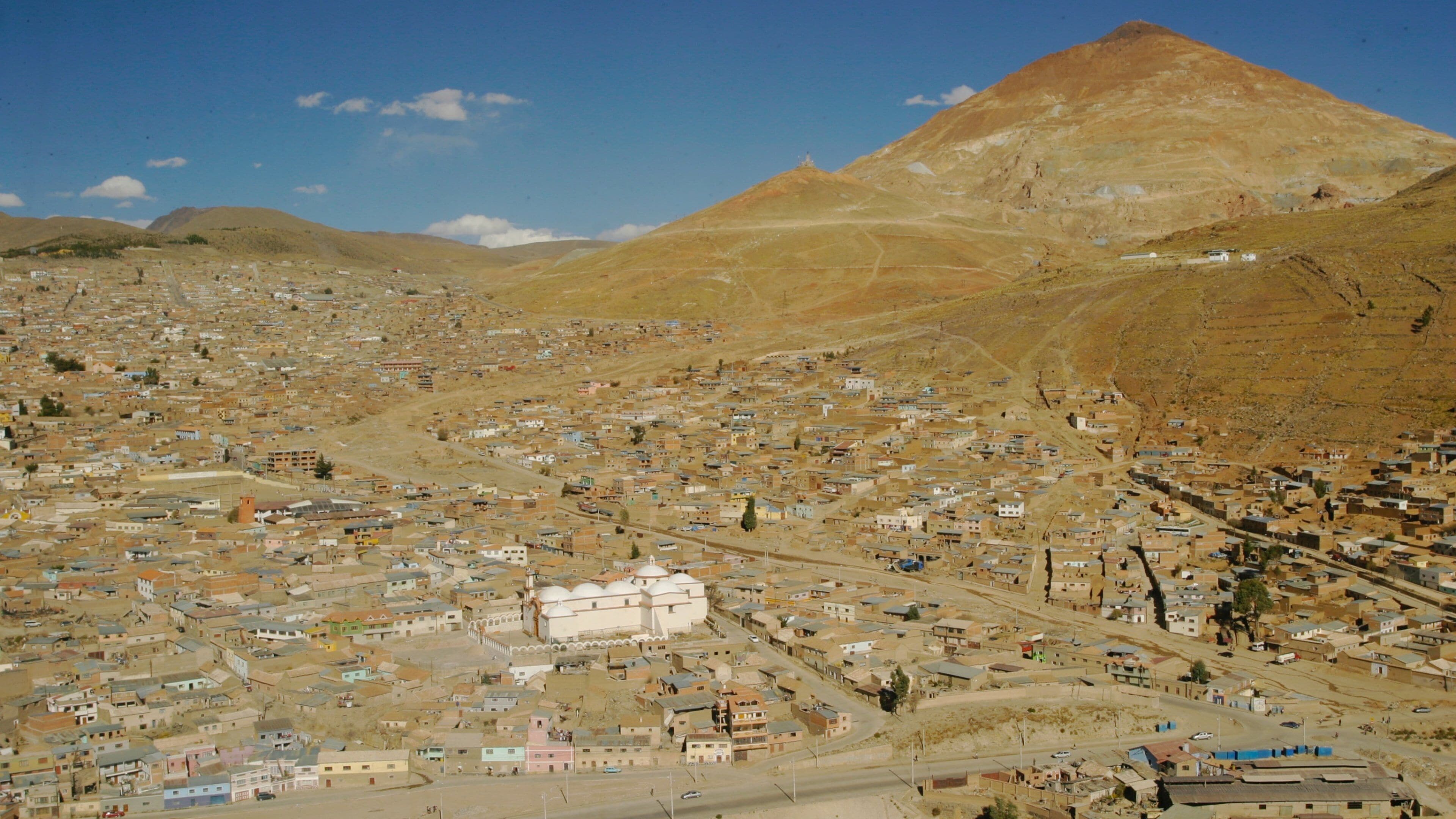 Un paisaje urbano con una montaña destacada al fondo.