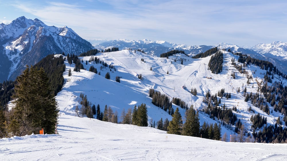 A snow-covered mountain range with ski slopes and a clear sky.