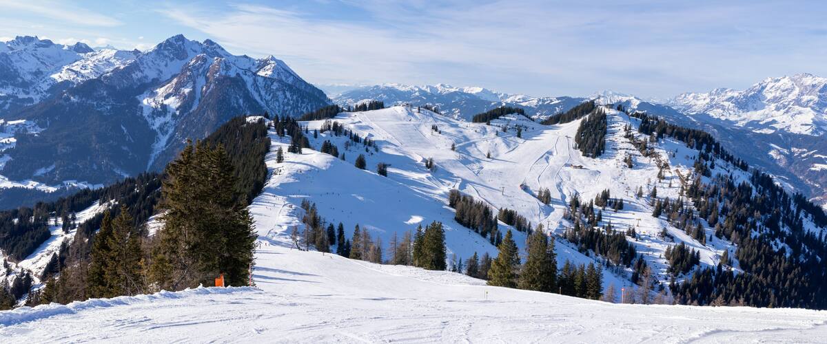 A snow-covered mountain range with ski slopes and a clear sky.