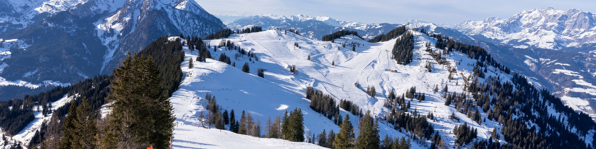A snow-covered mountain range with ski slopes and a clear sky.