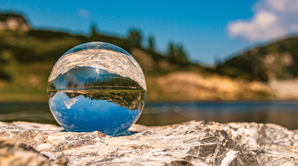 A clear glass sphere reflecting a mountainous landscape and a body of water.
