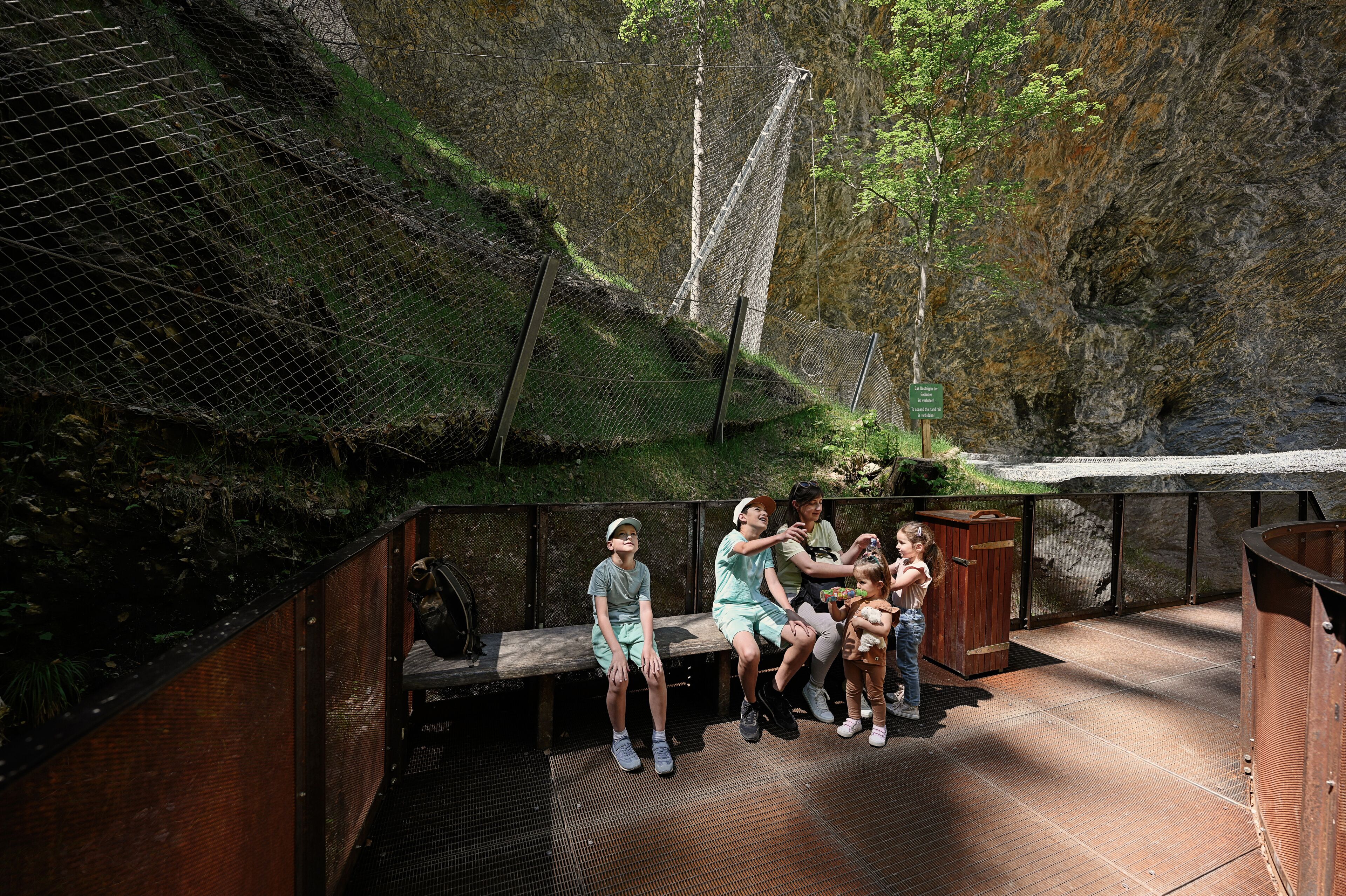 Mother with children sit on bench in Liechtensteinklamm or Liechtenstein Gorge, Austria.