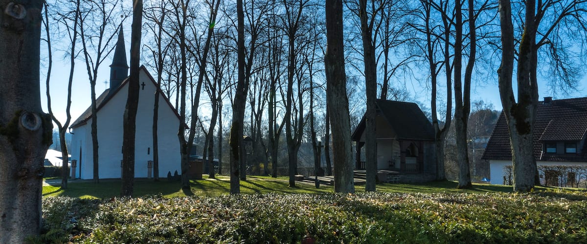 A serene village with a white church, stone buildings, and a clear blue sky.