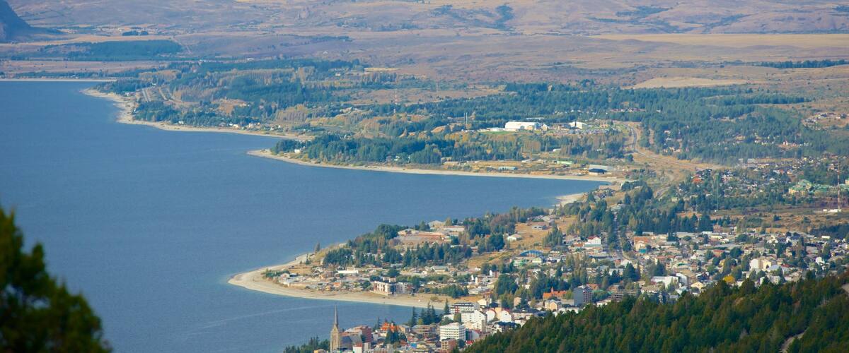 A coastal town with a beach, surrounded by mountains and dense forests.