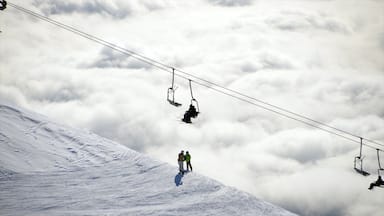 Pendiente nevada de montaña con un telesilla y esquiadores.