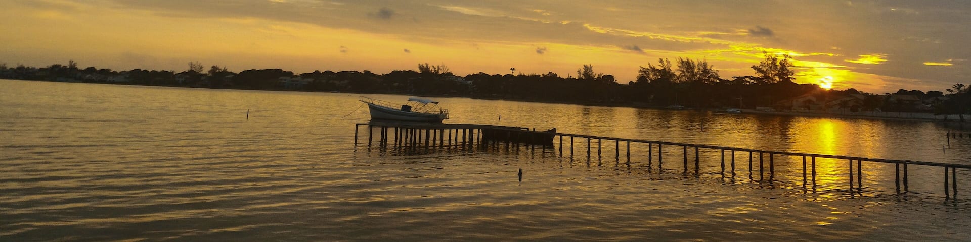 Beautiful nature sunset lights over Lagoon in Brazil. Tranquil scene for traveling and relaxation. Lake from São Pedro da Aldeia - Rio de Janeiro in a cloudy day lake with boats and silhoutte trees.