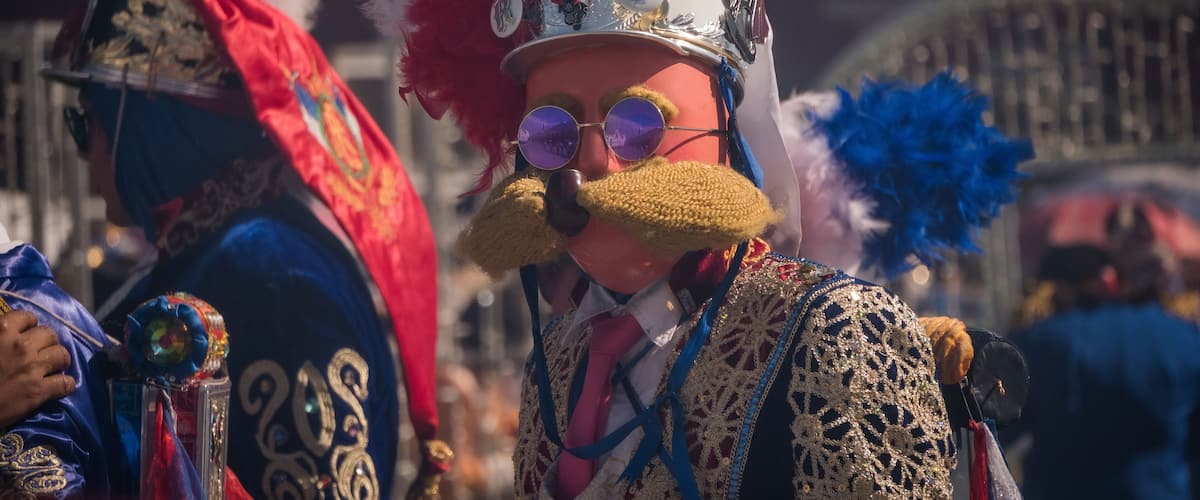 A person in elaborate, ornate costume with a large, decorative hat and a crown.