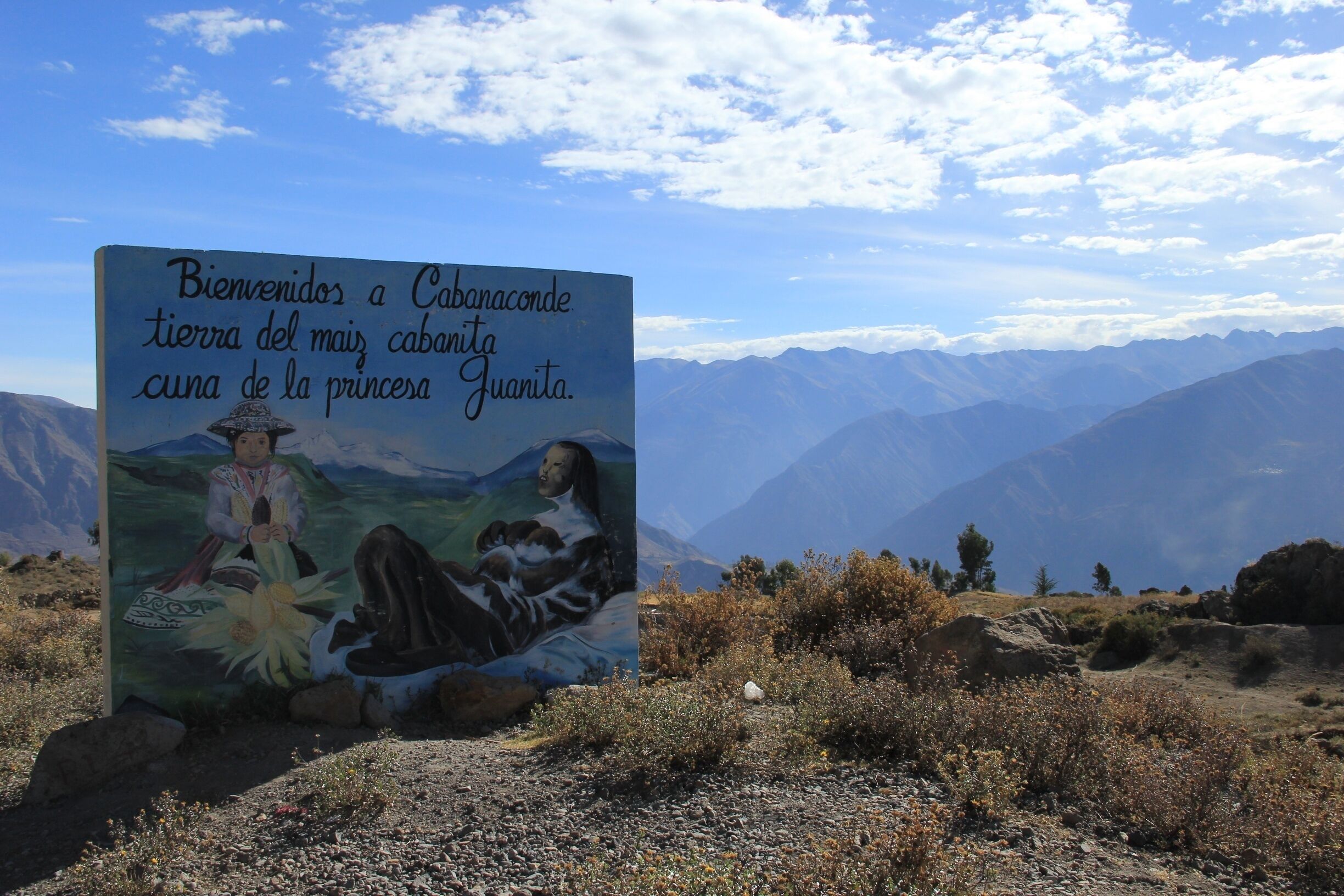 A sign with a painting of a woman and a child, and mountains in the background.